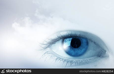 Eyes health. Female blue eye on cloudy sky background