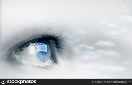 Eyes health. Female blue eye on cloudy sky background