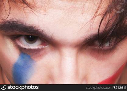 Eyes of handsome man with the red and blue paint on his face