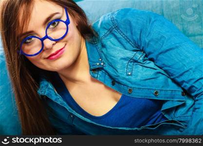 Eyewear. Young attractive woman face in blue glasses, closeup