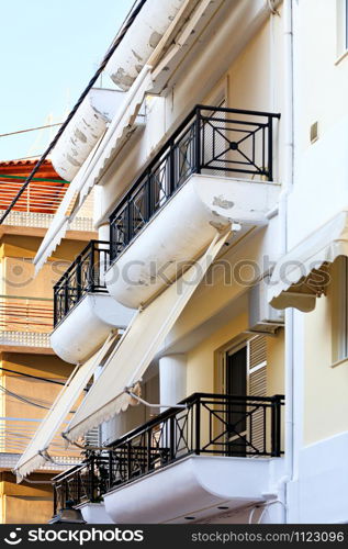 Fabric awnings on the balconies of buildings harmoniously combine with architecture and provide useful protection from harsh sunlight.. Balcony fabric awnings protect windows from sunlight.