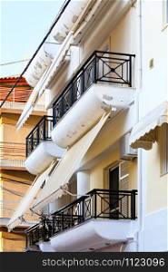 Fabric awnings on the balconies of buildings harmoniously combine with architecture and provide useful protection from harsh sunlight.. Balcony fabric awnings protect windows from sunlight.