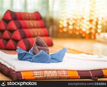 Fabric folded in flower shape with triangular pillow in vintage massage room with nature light source from window, Thailand