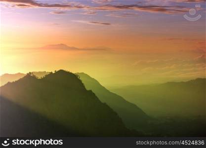 Fabulous light of sun rays at beautiful sunrise in mountains of Java island, Indonesia