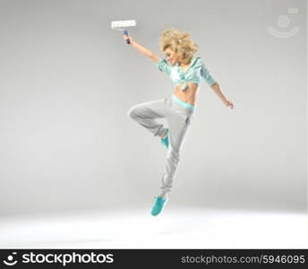 Fabulous shapely woman jumping with paint roller