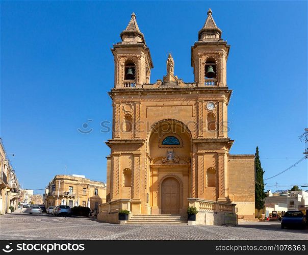 Facade and belfries of the old church of St. Peter on a sunny morning. Marsaxlokk. Malta.. Marsaxlokk. The building of the church of St. Peter on a sunny morning.