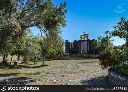 Facade of a former Orthodox monastery . Facade of a former Orthodox monastery among olive trees and flowers in the countryside of Crete