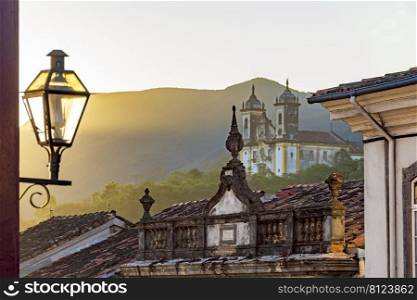 Facade of historic colonial style houses with their lanterns and church in the background in the city of Ouro Preto state of Minas Gerais, Brazil. Facade of historic colonial style houses with their lanterns