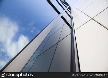 facade of white office building with reflections of very blue sky and clouds