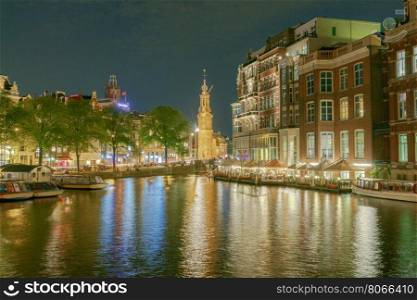 Facades of traditional Dutch houses on the canal in the night light. Amsterdam. Netherlands.. Amsterdam. Night view of the houses along the canal.