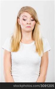 Face expression, emotions concept. Sad cute young blonde attractive woman in white t shirt.. Sad cute young blonde attractive woman