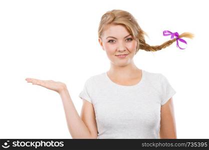 Face expression, happiness concept. Happy, cheerful teenage girl in blonde braid windblown hair presenting copyspace at palm hand. Studio shot isolated. Happy teenage girl in braid hair presenting hand