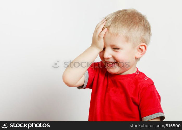 Face expressions, children concept. Portrait of happy kid boy making funny silly faces with hand on forehead. Happy kid boy making funny silly faces