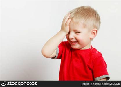 Face expressions, children concept. Portrait of happy kid boy making funny silly faces with hand on forehead. Happy kid boy making funny silly faces