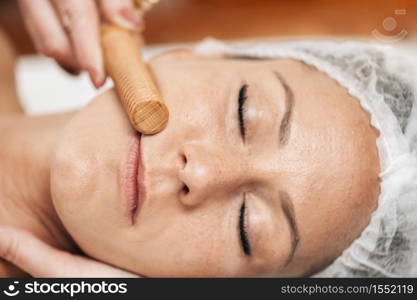 Face Massage. Anti-aging madero therapy face treatment with ribbed wooden stick at cosmetology center . Face Massage. Anti-Aging Madero therapy Face Treatment at Cosmetology Center