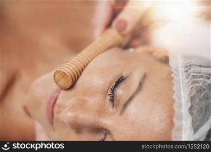 Face Massage. Anti-aging madero therapy face treatment with ribbed wooden stick at cosmetology center . Face Massage. Anti-Aging Madero therapy Face Treatment at Cosmetology Center