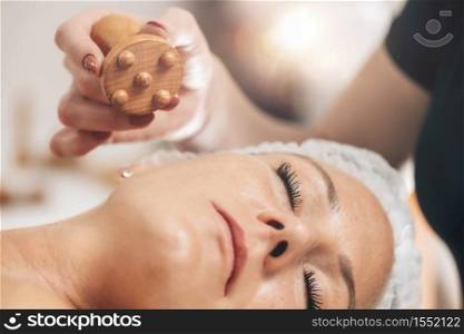 Face massage masseuse massaging woman&rsquo;s face with Madero therapy wooden massager. Face Massage with Madero Therapy Wooden Massager