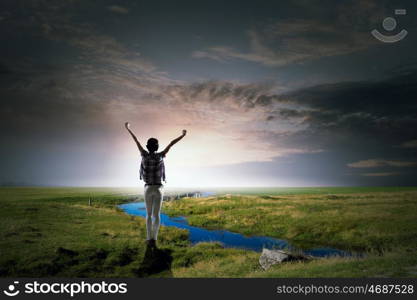 Face new day. Back view of cheerful woman with hands up facing sunrise