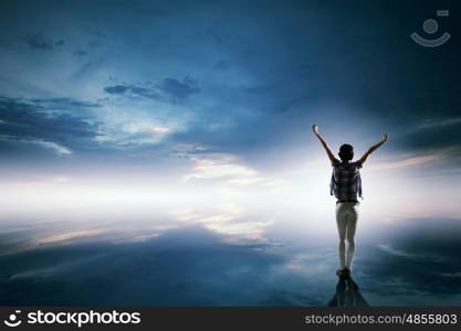 Face new day. Back view of cheerful woman with hands up facing sunrise