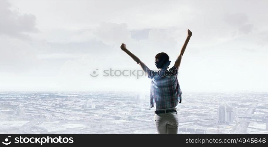 Face new day. Back view of cheerful woman with hands up facing sunrise