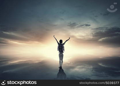 Face new day. Back view of cheerful woman with hands up facing sunrise