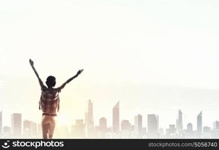 Face new day. Back view of cheerful woman with hands up facing sunrise