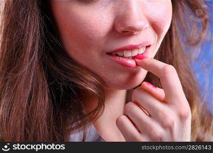 Face of a Pretty young woman touch to lips - on blue background