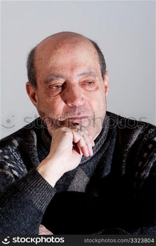 Face of an old man with little hair and bald spot and hand on his chin with serious expression, isolated.