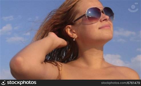 Face of cute girl in sunglasses on the beach against sky close-up
