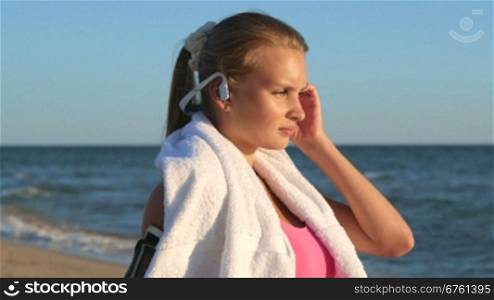 Face of fitness girl relax listening to music after workout on the beach