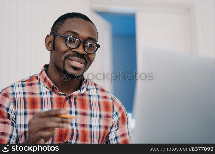 Face of positive afro man in glasses has online conference on pc. Businessman is talking to client. Teacher is speaking to student. Remote study, distance learning. Online courses.. Positive afro man in glasses has online conference on pc. Distance learning. Online courses.