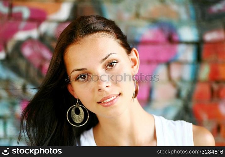 face of pretty brunette against colorful graffiti wall