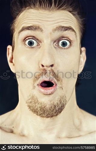 Face of surprised young man with his mouth open on black background