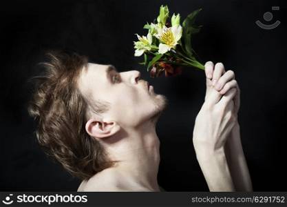 face of the young men sniffing bouquet of flowers on a black background