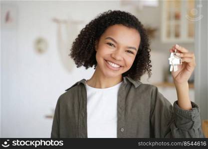 Face of young african american girl which is holding key from new apartment. Carefree teenager is smiling. Happy home owner is relocating. Mortgage loan and real estate purchase conceptual image.. Face of african american girl which is holding key from new apartment. Home owner is relocating.