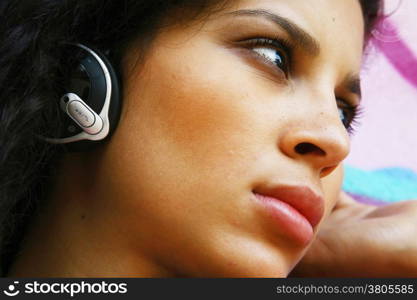 face of young beautiful girl listening to MP3 player on the street