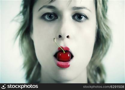 face of young beautiful girl with cherry in mouth