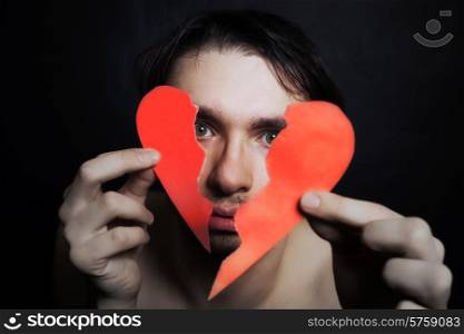 Face of young handsome man with broken paper heart closeup