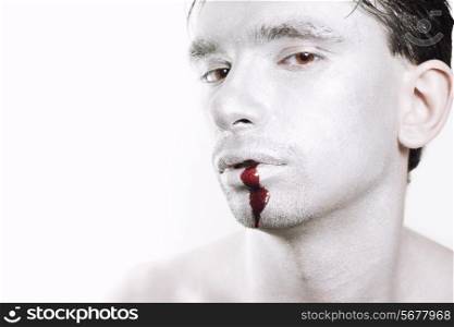Face of young man with silver makeup and blood closeup