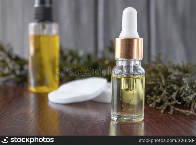 Face oil in a glass bottle on a dark background with cotton pads.. Face oil on a dark background with cotton pads.