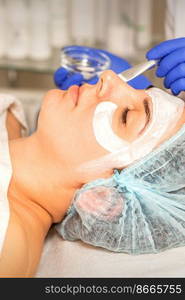 Face peeling at the beautician. Facial treatment. The beautician applies a cleansing face mask to the female patient. Face peeling at the beautician. Facial treatment. The beautician applies a cleansing face mask to the female patient.