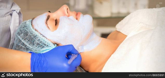 Face peeling at the beautician. Facial treatment. The beautician applies a cleansing face mask to the female patient. Face peeling at the beautician. Facial treatment. The beautician applies a cleansing face mask to the female patient.