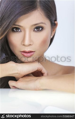 Face portrait of a beautiful nude sexy young Chinese Asian woman or girl resting on her hands