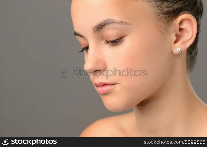 Face skin beauty teenage girl looking down close-up gray background