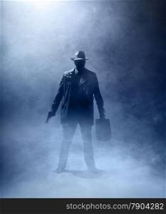 Faceles man with a gun and a briefcase standing in the fog.