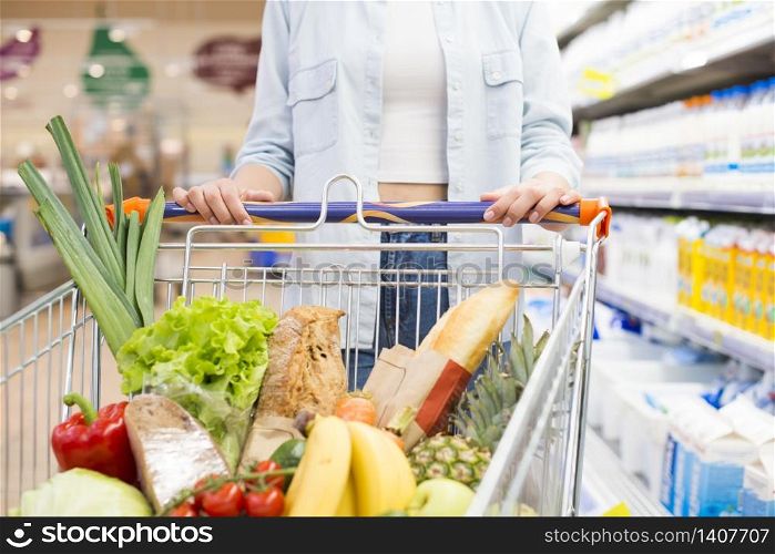 Faceless female driving shopping cart at supermarket