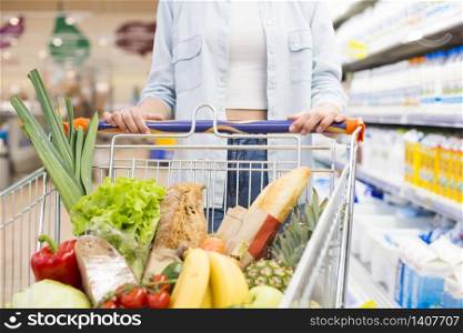 Faceless female driving shopping cart at supermarket
