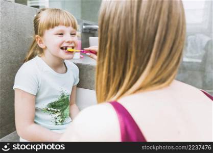faceless mother brushing teeth daughter
