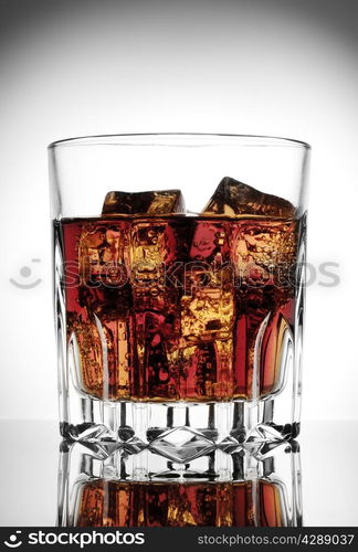 Faceted glass of cola with ice on a gradient background