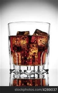 Faceted glass of cola with ice on a gradient background
